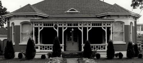 Façade of Building 20, showing the double front door, and the verandah with decorative woodwork and railing, 1988.; Department of National Defence / Ministère de la Défense nationale, 1988.