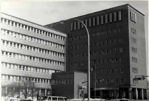 Corner view of the Surveys and Mapping Building, showing the recessed bands of windows with continuous stone sills, and continuous bands of stone above the windows forming ‘brise-soleil’ at each storey, 1994.; Parks Canada Agency / Agence Parcs Canada, 1994.