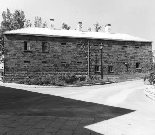 North-east elevation of Building No. 10, showing the hipped roof pierced by three brick chimneys and the irregularly placed windows, 1980.; Department of National Defence / Ministère de la Défense nationale, 1980.