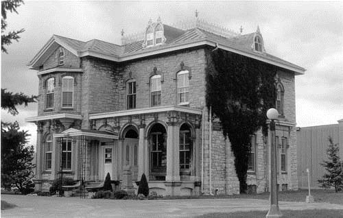 View of the Former Warden's Residence, showing its flat roofed porch with round-headed arches supported by piers faced with pilasters and stepped capitals, 1989.; Agence Parcs Canada / Parks Canada Agency, 1989.