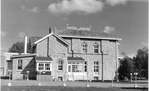View of the Former Warden's Residence, showing its square plan with an asymmetrically located projecting bay and rear service wing, 1989.; Agence Parcs Canada / Parks Canada Agency, 1989.