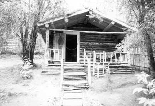 Façade of the Robert Service Cabin, showing the one-storey massing which consists of a two-room structure with a gable roof, 1987.; Parks Canada | Parcs Canada, 1987.