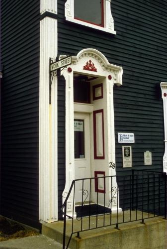 Detail photo of the main entrance - recessed and surrounded by panels.  Photo also shows other decorative elements. Date unknown.; HFNL 2007