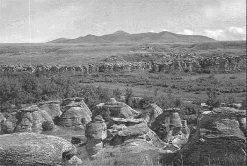 General view of Áísínai'pi, showing the “medicine rocks” and the distant Kàtoyissiksi (Sweetgrass Hills), 2002.; Parks Canada Agency/ Agence Parks Canada, 2002.
