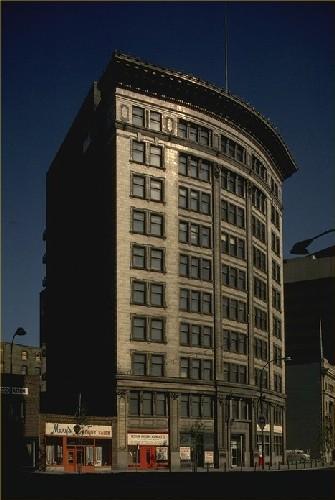 View of the Confederation Building, showing its curved white terracotta clad facade with overhanging cornice.; Agence Parcs Canada / Parks Canada Agency