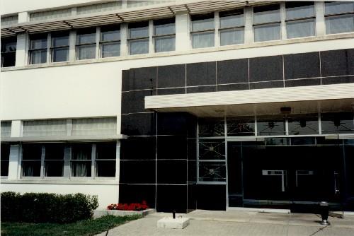 View of the main entrance to Building M-20, showing the use of smooth "modern" materials such as steel, glass block, white stucco and black marble veneer, 1991.; Parks Canada Agency / Agence Parcs Canada, J. Adell, 1991.