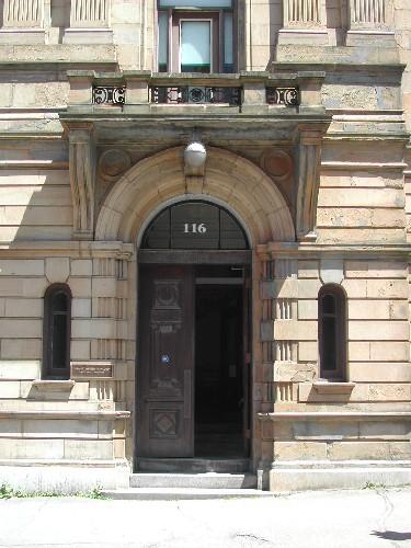 This photograph shows the entrance and the projecting flat stone hood with balustrade that forms a balcony, 2005; City of Saint John
