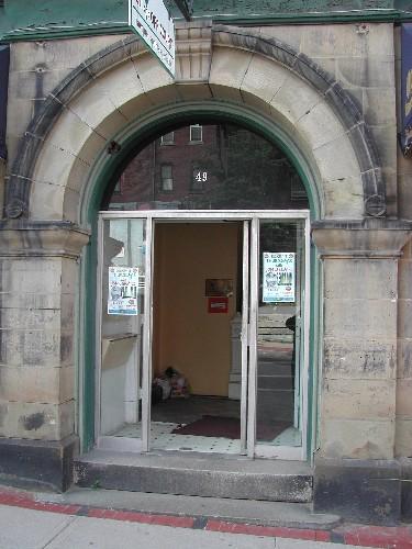 This photograph shows the Roman arch sandstone entranceway, and illustrates the keystone, transom window and large pilasters, 2005; City of Saint John