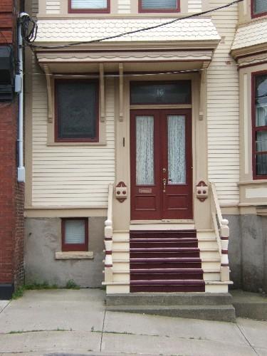 This photograph shows the main entrance below the upper storey bay window with long brackets, as well as the scalloped shingling, 2005; City of Saint John