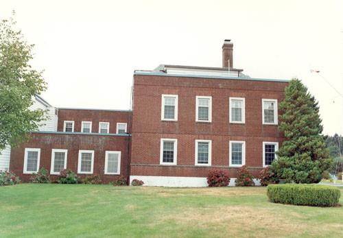 View of the east façade of Building 1, showing the elliptical windows with bold, white, concrete surrounds, 1990.; Parks Canada Agency / Agence Parcs Canada, 1990.