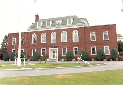 Front elevation of Building 1, showing the symmetry of its massing, in which three flat-roofed wings are set evenly around a central, hipped-roof section, 1990.; Parks Canada Agency / Agence Parcs Canada, 1990.