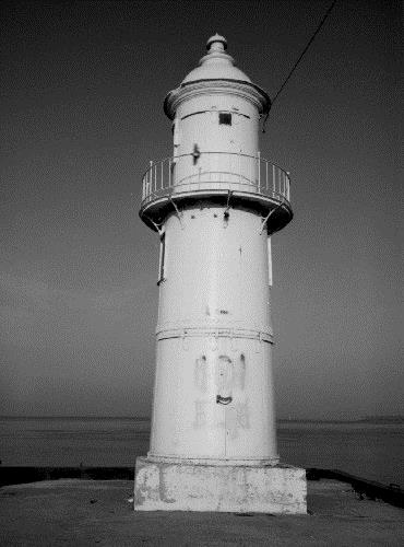 General view of the Light Tower (Front), showing the tapered massing composed of a concrete base, two cylindrical sections and an attractive metal cupola that houses the light apparatus, 1989.; Canadian Coast Guard / Garde côtière canadienne, 1989.