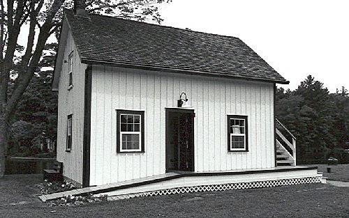 Corner view of the Storehouse, Lock Office, showing the gable roof and board-and-batten wood siding, 1989.; Public Works and Government Services Canada / Travaux publics et Services gouvernementaux Canada, 1989.