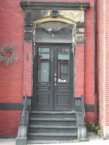 This photograph shows the entrance and the large sandstone entablature supported by brick pilasters, 2005; City of Saint john