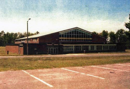 View of the main entrance to the Drill Hall, showing the contrasting volumes and roof lines of the building’s central gabled portion and the lower flat-roofed side bays, 2001.; Department of National Defence / Ministère de la Défense nationale, 2001.