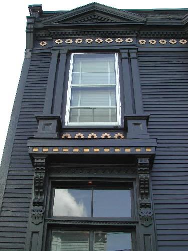 This photograph shows an upper window with Doric pilasters on each side, and illustrates the pediment above the frieze band, 2005; City of Saint John
