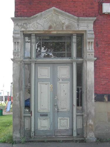 This photograph shows the entrance with sandstone pilasters and entablature, and illustrates the paired wooden door, sidelights and transom window, 2005; City of Saint John