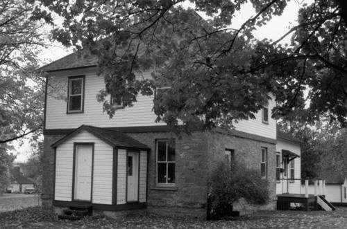 Corner view of the Defensible Lockmaster's House, showing the first floor exterior walls of thick evenly coursed masonry and the second floor with clapboard exterior, 1990.; Parks Canada Agency / Agence Parcs Canada, James De Jonge, 1990.