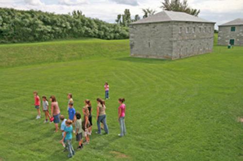 Corner view of the North Magazine with the clean and simple architectural treatment, including the regularity of the fenestration, which is consistent with the style evident in all of the buildings located around the parade ground, 2006.; Parks Canada Agency / Agence Parcs Canada, B. Aquin, 2006.