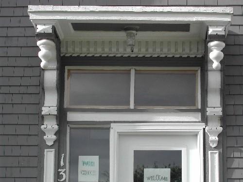 This photograph shows the entrance with ornate entablature, long ornate brackets, pendant finials, and transom window, 2005; City of Saint John