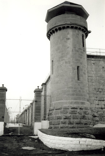 View of one of the Towers from inside the walls, showing the circular frame guardhouse, glazed on all sides, with a steep octagonal roof, 1990.; Parks Canada Agency / Agence Parcs Canada, Dana Johnson, 1990.