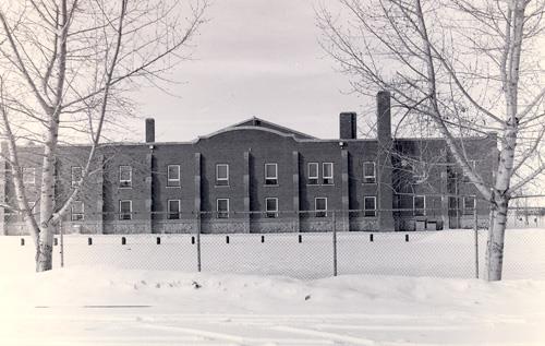 General view of the D.V. Currie VC Armoury, showing one of two two-storey wings that house offices, vaults for arms and equipment, classrooms, rifle ranges, and mess rooms, 1989.; Department of National Defence / Ministère de la Défense nationale, 1989.