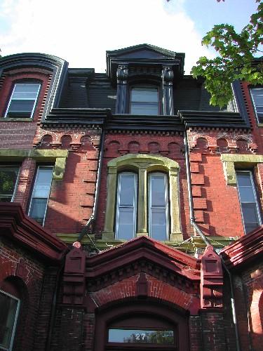 This photograph shows the middle of the front façade and illustrates the brick Roman arch motif, the pedimented dormer, and the double-set window, 2005; City of Saint John