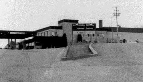 South-west elevation of the Border Crossing Facility, showing its sleek and bold International Style design and modern materials which dominate the highway and the agrarian landscape at the border, 1989.; Canada Revenue Agency / Agence du revenu du Canada, 1989.