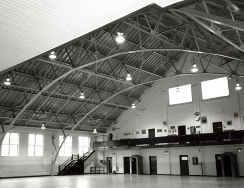 View of the interior of the Armoury, showing the large, open volume of the drill hall with exposed steel trusses, 1988.; Parks Canada Agency / Agence Parcs Canada, J. Hucker, 1988.
