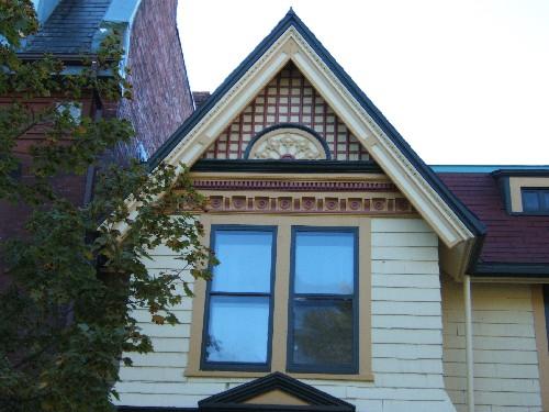 This photograph shows the top of the bay window with gable roof, and the ornate design in the tympanum, 2005; City of Saint John
