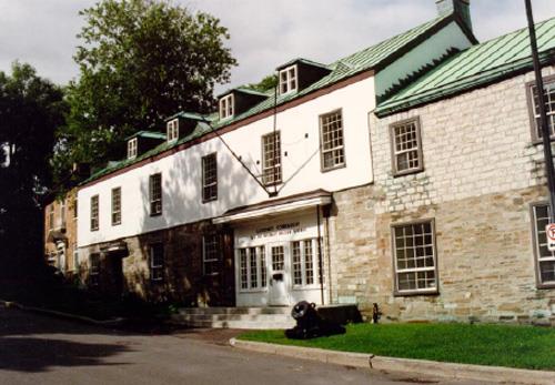 View of the main entrance of Building 2, showing the ground floor’s solid masonry construction and the stucco finish of the upper storey, 1993.; Parks Canada Agency / Agence Parcs Canada, Jocelyne Cossette, 1993.