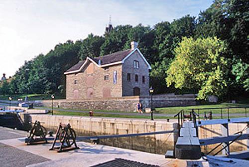 General view of the Commissariat Building emphasizing its imposing position within the Colonel By Valley, facing the Rideau Canal and overlooking its northern entrance, 2002.; Parks Canada Agency / Agence Parcs Canada, A. Guindon, 2002.
