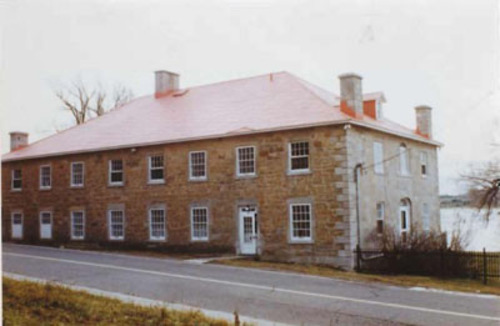 General view of the Carillon Barracks, showing the multi-paned, wooden sash windows along the side façade, 1977.; Parks Canada Agency / Agence Parcs Canada, 1977.