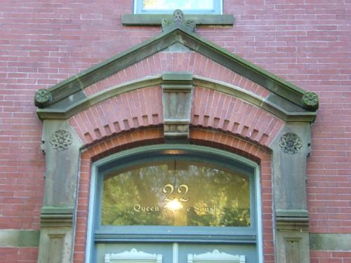 This photograph shows the entablature over the entrance, and illustrates the sandstone keystone, and segmented arch transom window, 2005; City of Saint John
