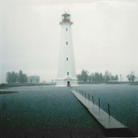 General view of the Light Tower, showing the building’s form and massing, tall profile and flared platform topped by an iron lantern, 1986.; Canadian Coast Guard / Garde côtière canadienne, 1986.
