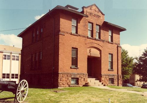 View of the façade of the PEIR Armoury, showing the exterior details, executed in red brick, including corner buttresses and a semi-circular arch above the main entrance, 1984.; Department of National Defence / Ministère de la Défense nationale, 1984.