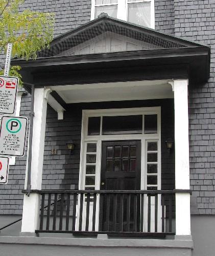 This image provides a view of the pedimented portico, the transom window, the sidelights and the wooden door with multiple glass panels, 2005; City of Saint John