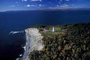 View of the Light Tower at Gaspé Cape, showing its adjacent buildings and coastal surroundings, 1989.; Agence Parcs Canada / Parks Canada Agency, N. Boisvert, 2003.