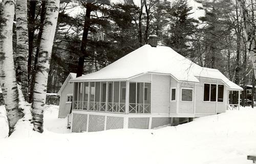 General view of the Guest Cottage, showing enclosed verandah and the one-storey massing with a hipped roof and chimney.; Parks Canada Agency / Agence Parcs Canada.