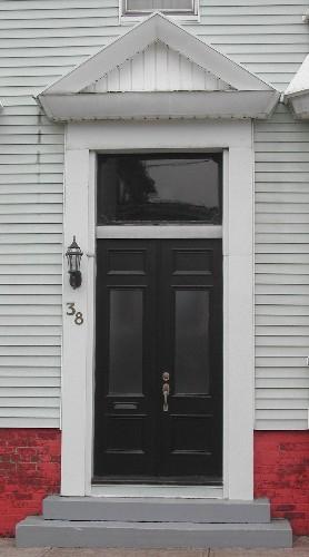 This image provides a view of the entry consisting of a pediment above a transom window and paired wood doors with glass panels, 2005; City of Saint John