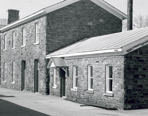 View of the exterior of the Workshop, showing the exterior walls of random coursed red sandstone, 1985.; Parks Canada Agency / Agence Parcs Canada, 1985.