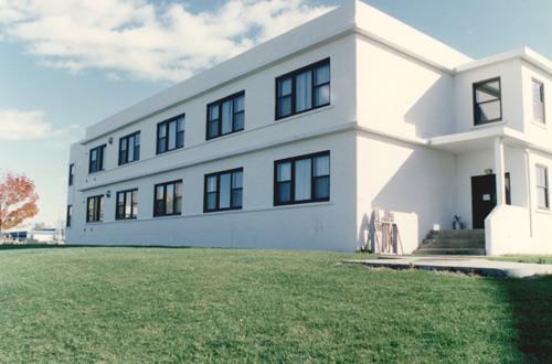 View of the exterior of Building B-39, showing the concrete construction with white painted stucco cladding, 1993.; Parks Canada Agency / Agence Parcs Canada, 1993.