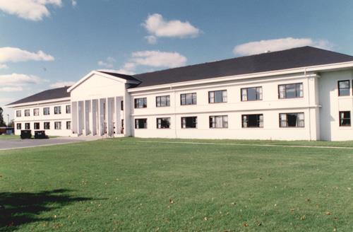 View of the main entrance of Building B-37, showing the articulated corner accents, the emphasized and elaborated principal entrance with projecting portico, and the recessed entrance of classical derivation, 1993.; Parks Canada Agency / Agence Parcs Canada, 1993.