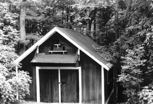 View of the exterior of the Forge, showing the wood-frame construction clad in vertical board siding with white trim, 1984.; Parks Canada Agency / Agence Parcs Canada, M. Trépanier, 1984.