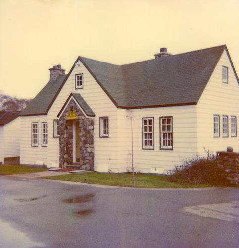 General view of the Administration Building, showing its symmetrically disposed façade with a central stone-faced porch that shelters the main entrance, 1990.; Parks Canada Agency / Agence Parcs Canada, 1990.