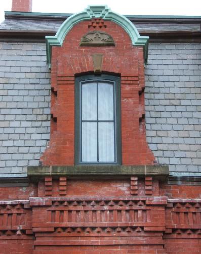 This image provides a view of the brick dormer crowned by a rounded pediment above the cornice supported by corbelled brackets, 2005.
; City of Saint John
