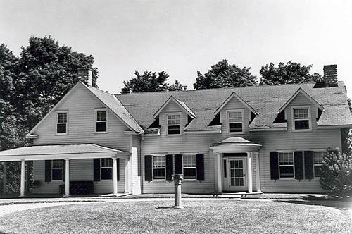 Rear view of the Farm House, showing the horizontal wood cladding and the multi-pane wood windows and shutters.; National Archives of Canada  / Archives nationales du Canada, PA 129813.