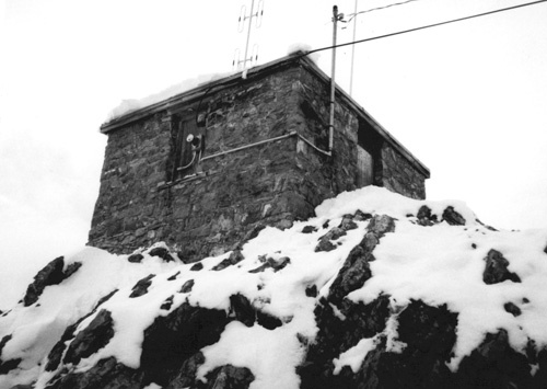 Side view of Sulphur Mountain Weather Station, showing its simple, one-storey massing with a hipped roof, 1986.; Environment Canada, Parks Canada, Western Regional Office, 1986 / Environnement Canada, Parcs Canada, Bureau de la région de l'Ouest, 1986.