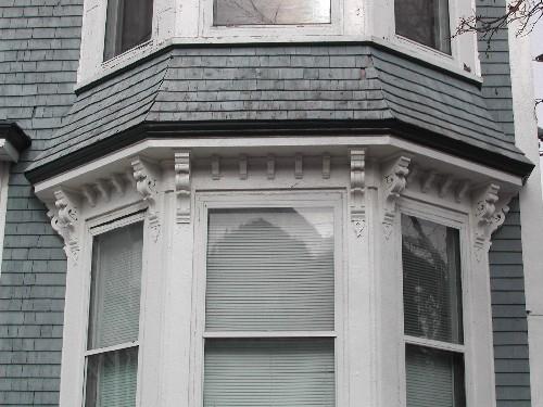 This photograph shows the flared bracketed cornice between the first and second floor of the bay window, 2005; City of Saint John