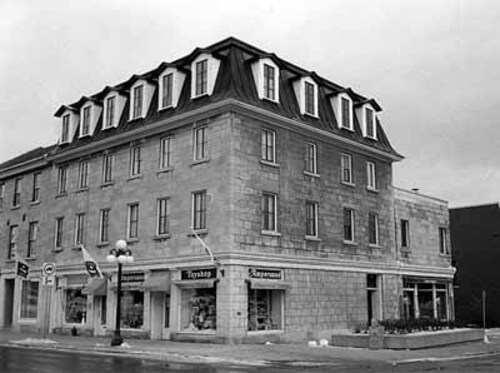 Corner view of the Commercial Building, showing the mansard roof with regularly placed gabled dormers set over regularly placed windows, 1986.; Parks Canada | Parcs Canada, D. Johnson, 1986.